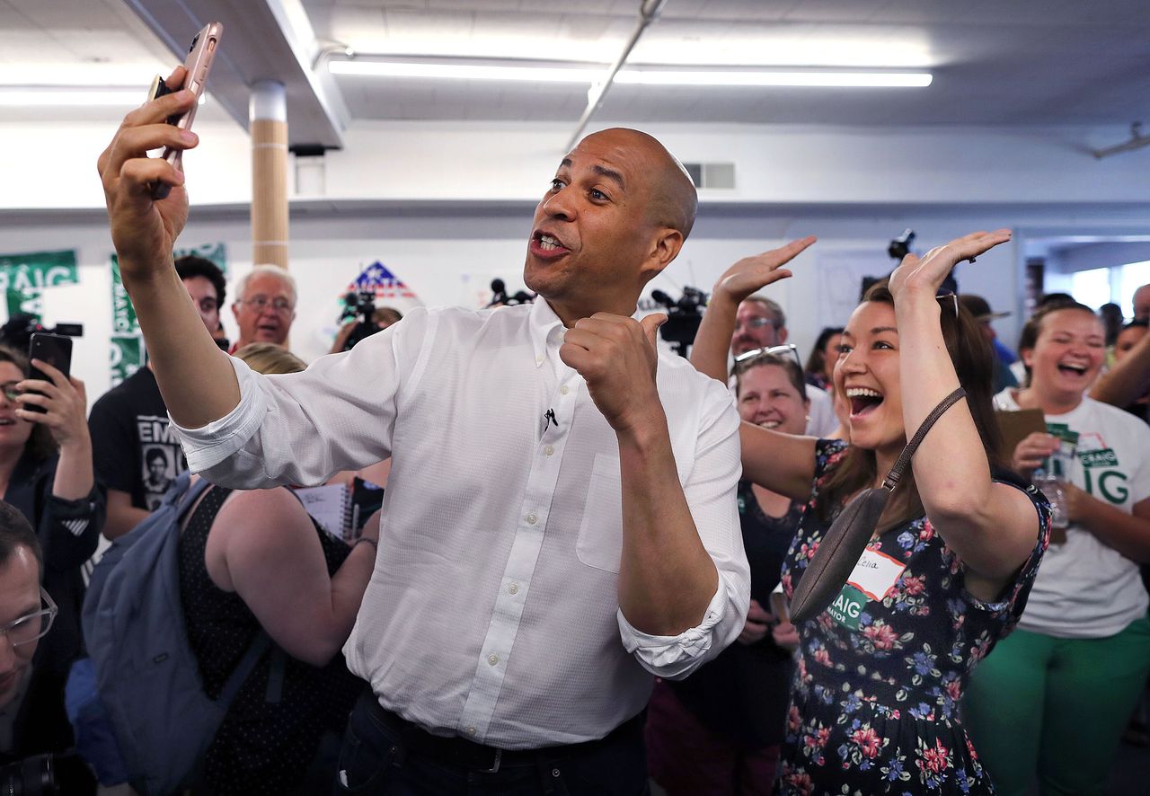 Booker records a video of himself using Celia Botto's phone as she cheers behind him during a campaign stop in Manchester, New Hampshire, on July 13.