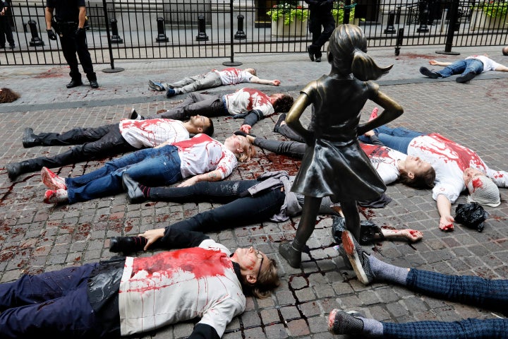 Activists with the Extinction Rebellion movement demonstrate outside the New York Stock Exchange and the Defiant Girl statue,