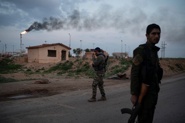 A US-backed Syrian Democratic Forces (SDF) fighter talks on his radio at a check point near Omar oil field base, eastern Syria, Sunday, Feb. 24, 2019.