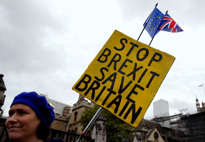 An anti-Brexit campaigner holds a banner near Parliament in London, Tuesday, Oct. 8, 2019. The British government said Tuesday that the chances of a Brexit deal with the European Union were fading fast, as the two sides remained unwilling to shift from their entrenched positions. (AP Photo/Kirsty Wigglesworth)