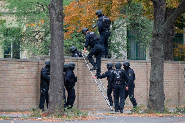 Police officers cross a wall at a crime scene in Halle, Germany, Wednesday, Oct. 9, 2019.