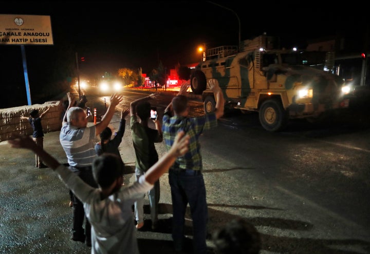 Local residents jeer and applaud as a convoy of Turkish forces vehicles and trucks carrying tanks and armoured personnel carriers is driven in Sanliurfa province, southeastern Turkey.