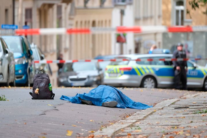 A person lies on a road in Halle, Germany, Wednesday, Oct. 9, 2019. A gunman fired several shots on Wednesday in German city of Halle and at least two got killed, according to local media FOCUS online.The gunman is on the run and police have sealed off the surrounding area. (Sebastian Willnow/dpa via AP)