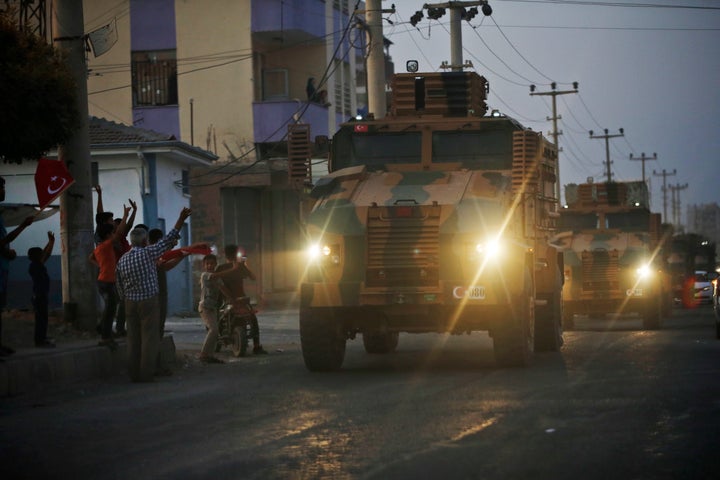 Local residents cheer and applaud as a convoy of Turkish forces vehicles is driven through the town of Akcakale, Sanliurfa province, southeastern Turkey, at the border between Turkey and Syria, Wednesday, Oct. 9, 2019. 