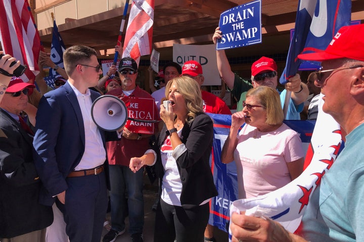 Arizona Republican Party Chairman Kelli Ward speaks to a crowd outside a field office for Rep. Tom O’Halleran, D-Ariz., as GOP spokesman Zachery Henry holds the bullhorn on Tuesday, Oct. 8, 2019, in Casa Grande, Ariz. 