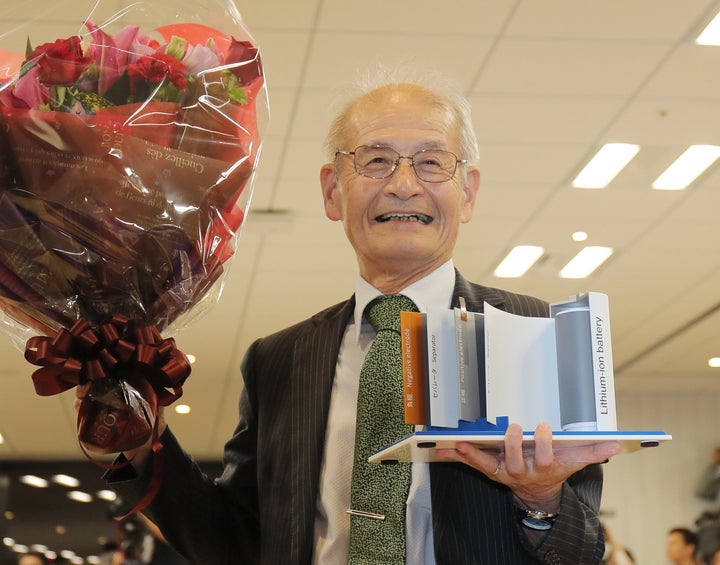 リチウムイオン電池の模型(右)と花束を手にする旭化成名誉フェローの吉野彰氏=9日、東京都千代田区