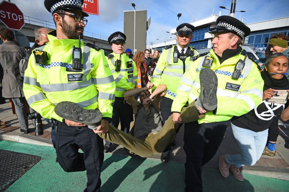 A man is removed by police officers after activists staged a 'Hong Kong style' blockage of the exit from the train station to City Airport, London