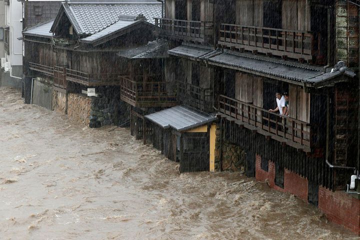 People watch the Isuzu River swollen by Typhoon Hagibis, in Ise, central Japan Saturday, Oct. 12, 2019. Tokyo and surrounding areas braced for a powerful typhoon forecast as the worst in six decades, with streets and trains stations unusually quiet Saturday as rain poured over the city. (Kyodo News via AP)