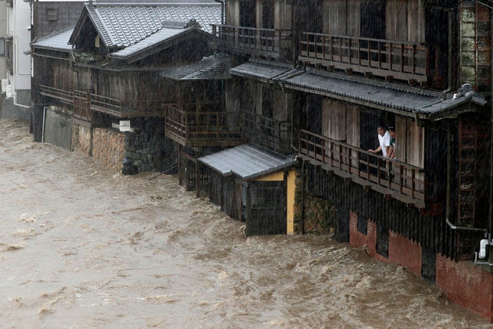 People watch the Isuzu River swollen by Typhoon Hagibis, in Ise, central Japan Saturday, Oct. 12, 2019. Tokyo and surrounding