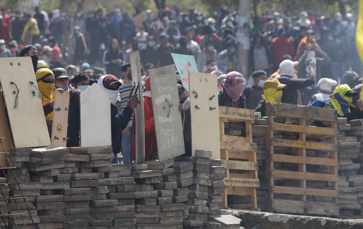 Anti-government demonstrators takes cover behind a barricade during clashes with police in Quito, Ecuador, Saturday, Oct. 12, 2019. Protests, which began when President Lenin Moreno's decision to cut subsidies led to a sharp increase in fuel prices, have persisted for days. (AP Photo/Fernando Vergara)
