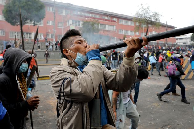 An indigenous anti-government demonstrator fires a blowgun during clashes with police in Quito, Ecuador, Friday, Oct. 11, 2019. Protests, which began when President Lenin Moreno's decision to cut subsidies led to a sharp increase in fuel prices, have persisted for days. (AP Photo/Fernando Vergara)