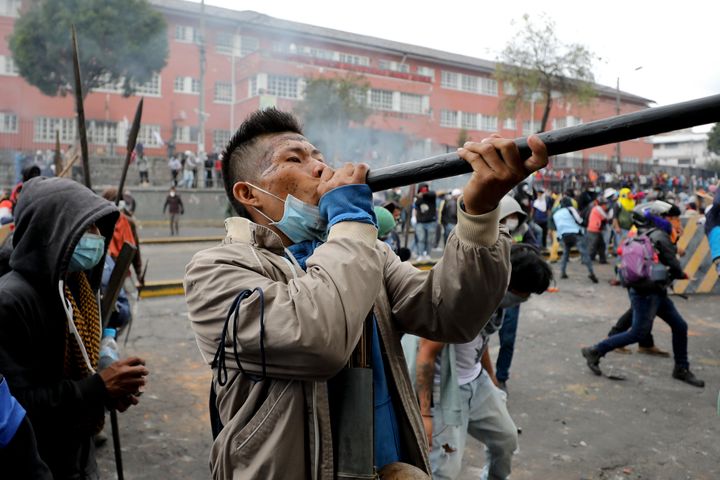 An indigenous anti-government demonstrator fires a blowgun during clashes with police in Quito, Ecuador, Friday, Oct. 11, 2019. Protests, which began when President Lenin Moreno's decision to cut subsidies led to a sharp increase in fuel prices, have persisted for days. (AP Photo/Fernando Vergara)