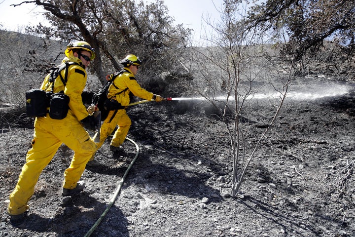 Brett Palmer, left, Anthony Ayala with the South Placer Fire Dept. hose down hot spot from a wildfire Saturday, Oct. 12, 2019, in Porter Ranch, Calif. 