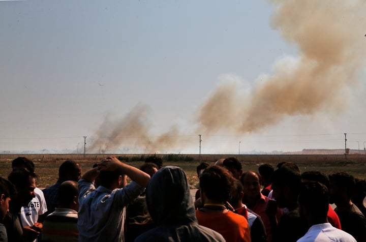 People watch from Akcakale, Sanliurfa province, southeastern Turkey, as smoke billows from fires on targets in Tel Abyad, Syria, caused by bombardment by Turkish forces, Sunday, Oct. 13, 2019. (AP Photo/Lefteris Pitarakis)