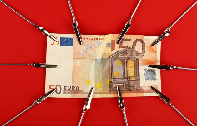 Close up one fifty Euro paper currency banknote pulled and stretched over red background with copy space, high angle view