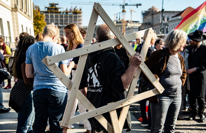 A demonstrator with a large wooden star of David over his shoulder participates in a protest against anti-Semitism.
