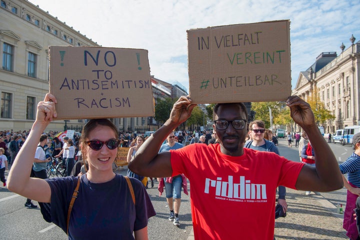 Hannah (26) and Kemo (30) hold posters with the inscription "No to Antisemitism and Racism" and "United in Diversity - #Indivisible" at a demonstration against anti-Semitism.