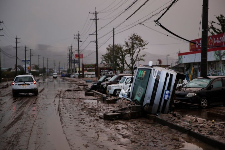 Typhoon-damaged cars sit on the street covered with mud on Monday in Hoyasu, Japan. Rescue crews in Japan dug through mudslides and searched near swollen rivers Monday as they looked for those missing after Typhoon Hagibis struck.