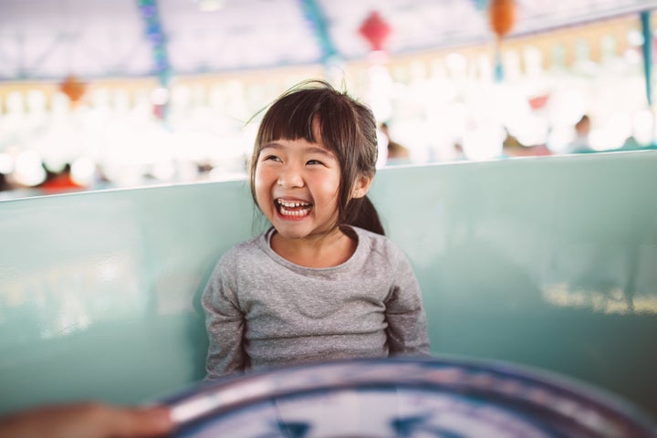 Lovely little girl riding on the amusement park ride joyfully.