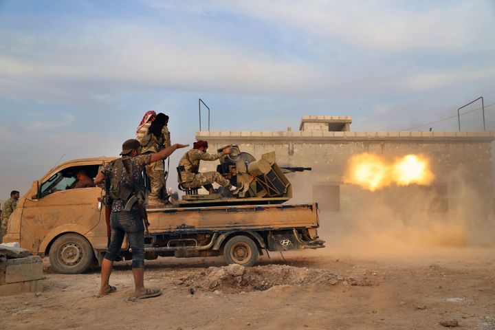 In this Monday, Oct. 14, 2019 photo, Turkey-backed Syrian opposition fighters fire a heavy machine-gun towards Kurdish fighters, in Syria's northern region of Manbij.