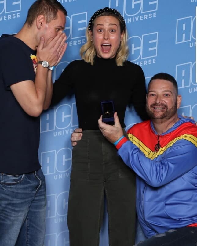 Brie Larson (center) was caught off-guard this weekend when fan John Chambrone (right) used his Comic-Con meet-and-greet with the "Captain Marvel" star to propose to his boyfriend, Richard Owen. 