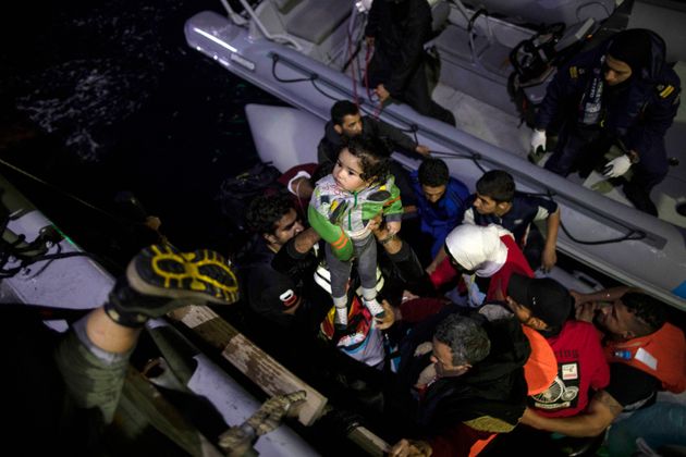 Πρόσφυγες και μετανάστες μεταφέρονται από το φουσκωτό σκάφος τους σε πλοιάριο της ελληνικής ακτοφυλακής, κατά τη διάρκεια μιας επιχείρησης διάσωσης κοντά στο νησί της Σάμου.