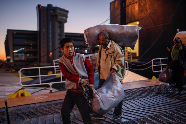Μετανάστες και πρόσφυγες κουβαλούν τα υπάρχοντά τους, καθώς αποβιβάζονται από ένα πλοίο στο λιμάνι του Πειραιά. Οι ελληνικές αρχές έχουν επιταχύνει τις προσπάθειές τους για την μετακίνηση χιλιάδων μεταναστών από την συνωστισμένη Μόρια στην ηπειρωτική χώρα.