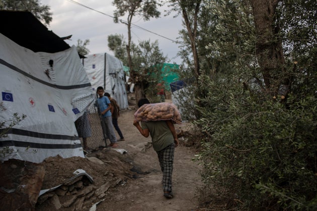 Προσφυγόπουλο από το Αφγανιστάν κουβαλάει στην πλάτη του ένα σακί με πατάτες, στη Μόρια της Λέσβου.