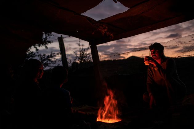 Ανθρωποι από το Αφγανιστάν πίνουν τσάι πάνω από τη φωτιά ενός αυτοσχέδιου μαγκαλιού στη Μόρια.