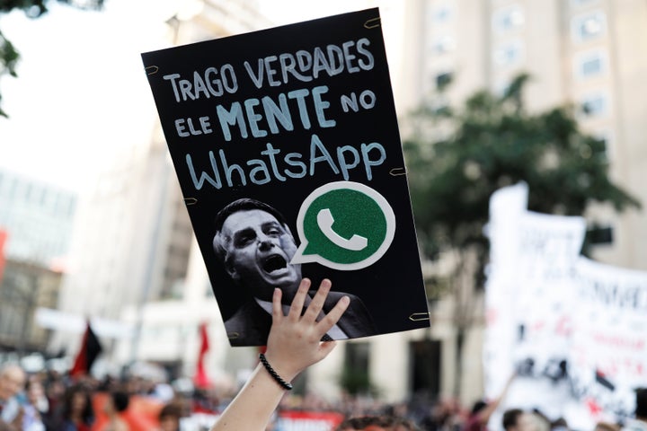 A woman holds a sign with an image of Jair Bolsonaro that reads "He lies in WhatsApp" during a protest against then-presidential candidate Bolsonaro in October 2018 in São Paulo.