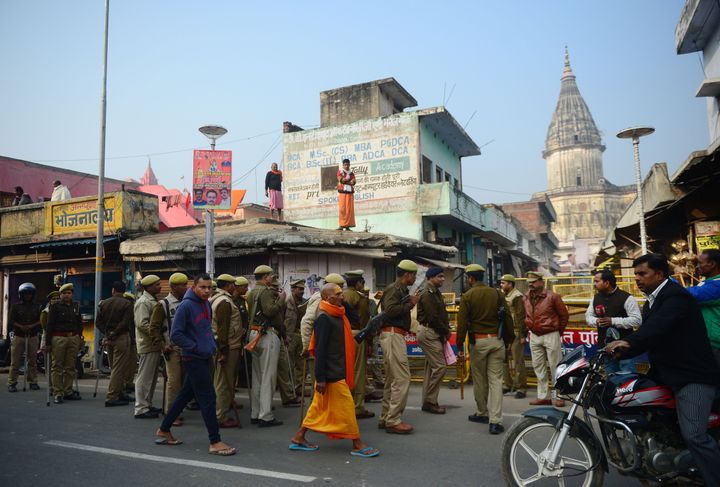 A sadhu walks past security personnel gathered on a street during the 26th anniversary of the demolition of the Babri mosque, in Ayodhya on December 6, 2018.