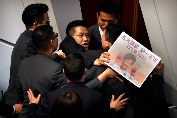 Pro-democracy lawmaker Gary Fan, center, is forcibly removed by security officials as he protests while Hong Kong Chief Executive Carrie Lam delivers her speech at a question and answer session at the Legislative Council in Hong Kong, Thursday, Oct. 17, 2019. (AP Photo/Mark Schiefelbein)
