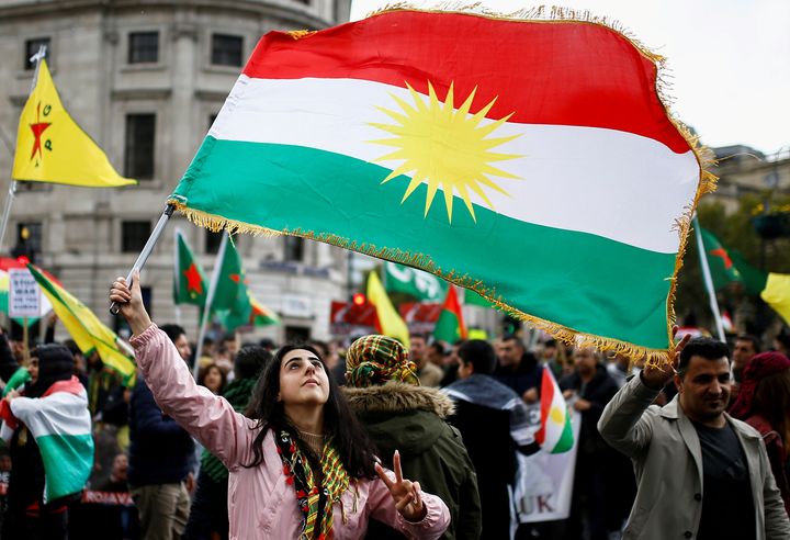 「クルドの旗」を掲げる女性。トルコのシリア侵攻に反対するイギリス・ロンドンのデモより