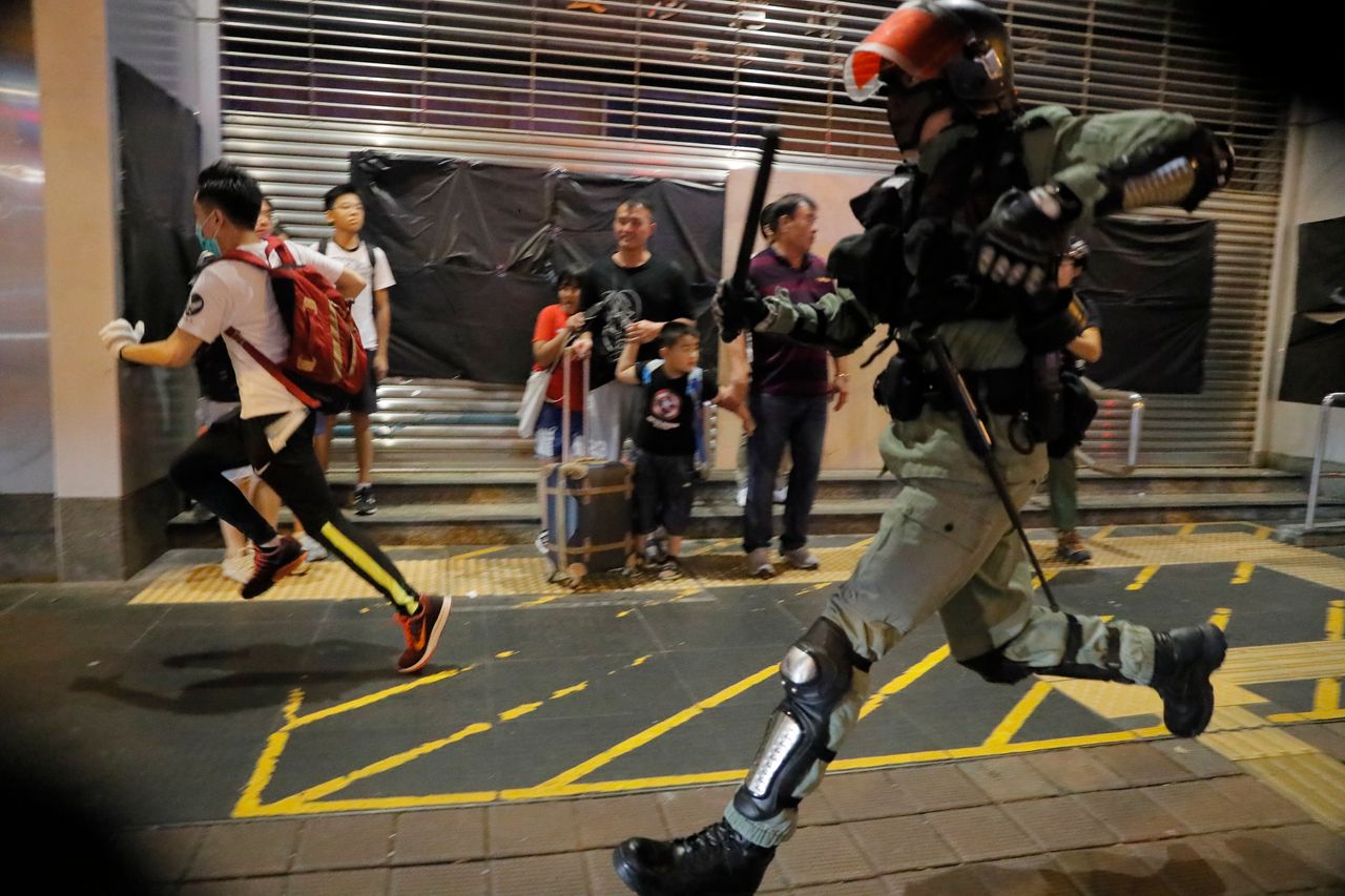 Police chase a protester in Hong Kong, Sunday, Oct.13, 2019. Protesters changed tactics and popped up in small groups in multiple locations across the city Sunday rather than gather in one large demonstration, pursued by police who swooped in to make muscular arrests. (AP Photo/Kin Cheung)