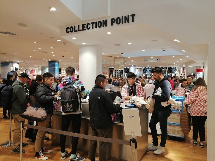 Jóvenes hacen cola para pagar en la caja de la tienda de Uniqlo con varias camisetas de Kaws cada uno.