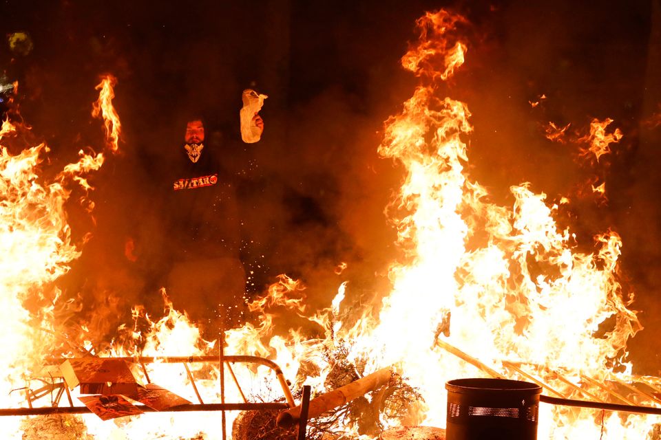 A protestors pours gasoline on a burning barricade during clashes with police in Barcelona, Spain, Thursday, Oct. 17, 2019. Catalonia's separatist leader vowed Thursday to hold a new vote to secede from Spain in less than two years as the embattled northeastern region grapples with a wave of violence that has tarnished a movement proud of its peaceful activism. (AP Photo/Emilio Morenatti)
