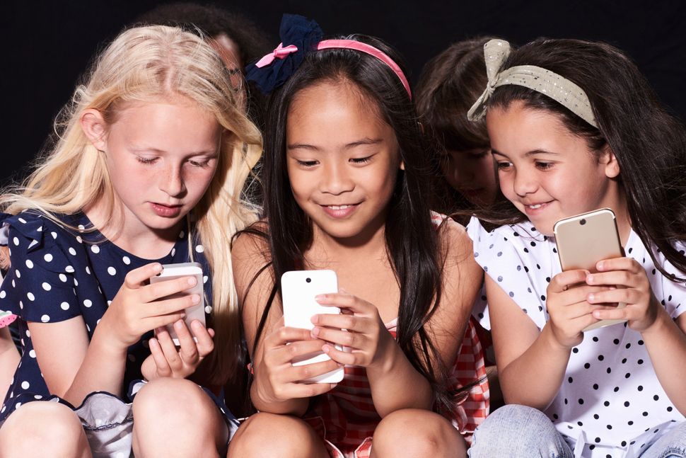 Τρία κορίτσια μικρής ηλικίας χρησιμοποιούν τα κινητά τους. 