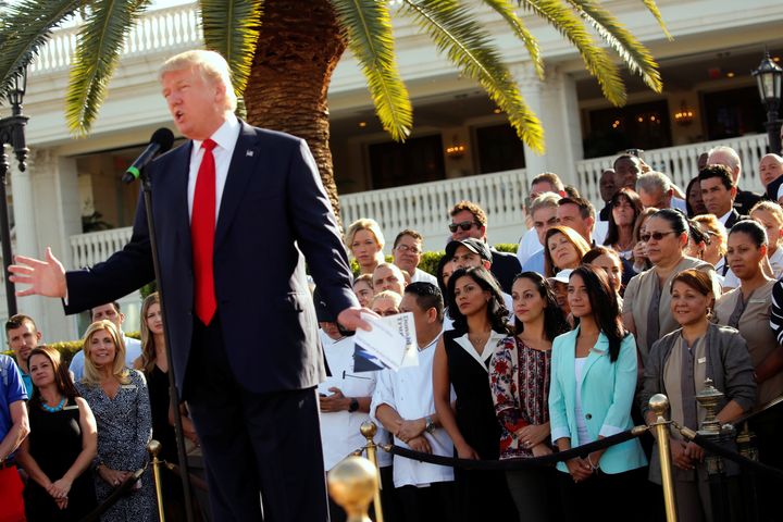 Employees of then-GOP presidential nominee Donald Trump stand behind him at a campaign event at his Trump National Doral golf club in Miami on Oct. 25, 2016. 