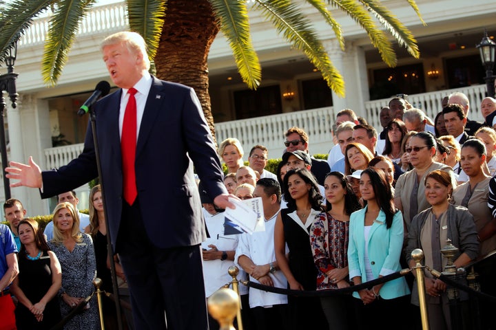 Employees of then-GOP presidential nominee Donald Trump stand behind him at a campaign event at his Trump National Doral golf