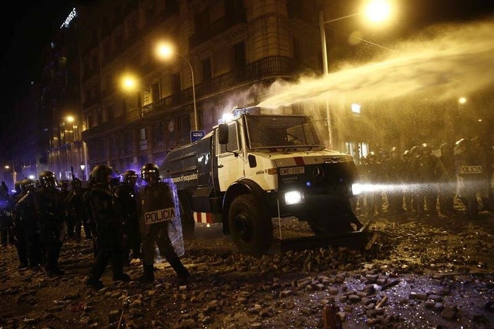 Un grupo de policías antidisturbios junto a la tanqueta de agua a presión.