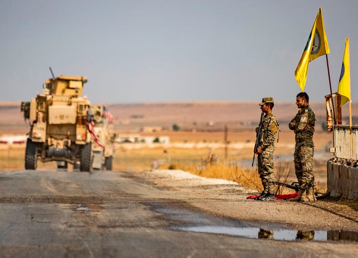 US military vehicles drive on a street in the town of Tal Tamr on Sunday after pulling out of their base.