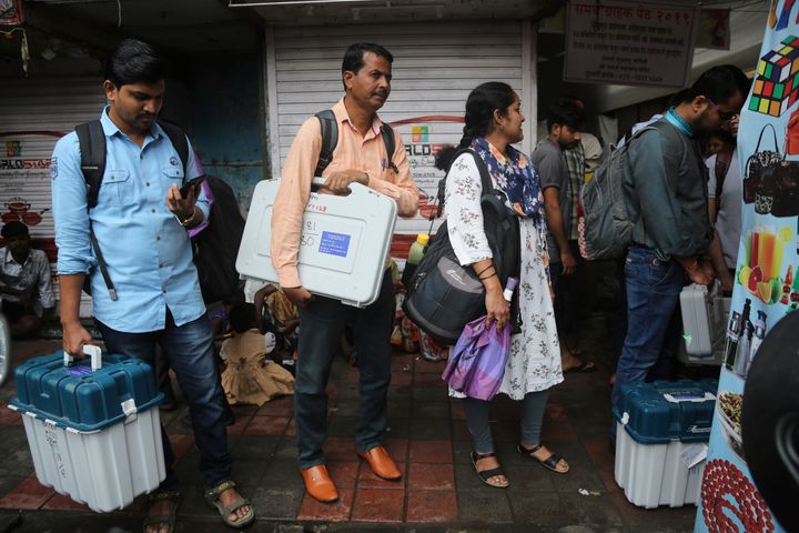 Polling officials hold electronic voting machines and other polling material in Mumbai, Oct 20, 2019.