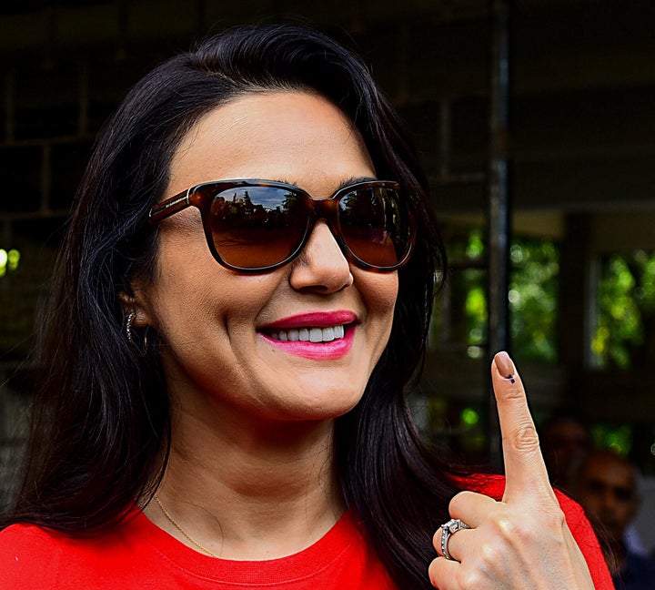 Bollywood actress Preity Zinta shows her inked finger after casting her vote at a polling station.