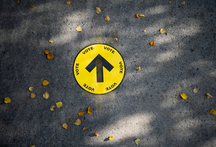 Un panneau indiquant aux électeurs un bureau de vote est collé sur le trottoir parmi les feuilles d'automne, le jour de l'élection fédérale de 2019, à Ottawa (Ontario), le lundi 21 octobre 2019.