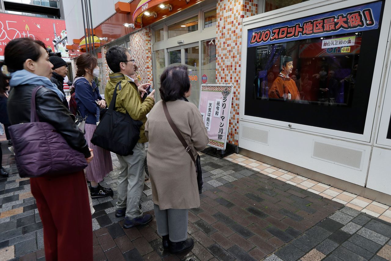 People stop and watch as the enthronement ceremony for the 59-year-old Emperor Naruhito is broadcasted live on television, Tuesday, Oct. 22, 2019, in Tokyo, Japan. (AP Photo/Aaron Favila)