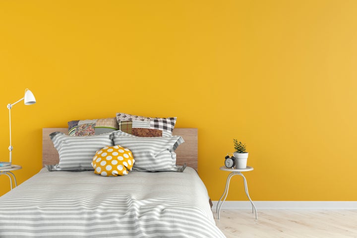 Bedroom with decoration on white hardwood floor in front of empty yellow wall with copy space. 3D rendered image.