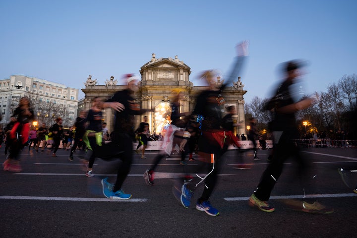 Corredores de la San Silvestre vallecana a su paso por la Puerta de Alcalá en Madrid. 