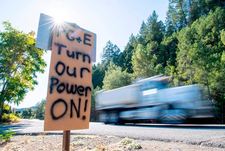 A sign calling for PG&E to turn the power back on is seen on the side of the road during a statewide blackout in Calistog