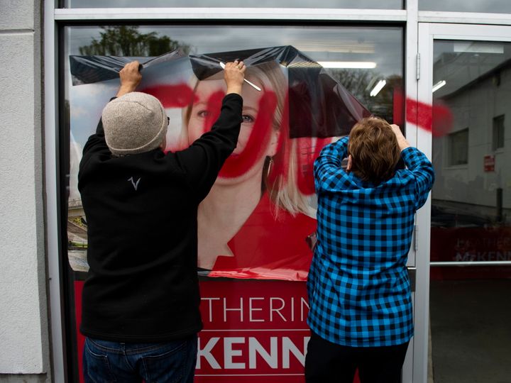 Campaign team members remove a defaced window decal from a window of Liberal MP Catherine McKenna's campaign office, on Wednesday, Oct. 24, 2019.