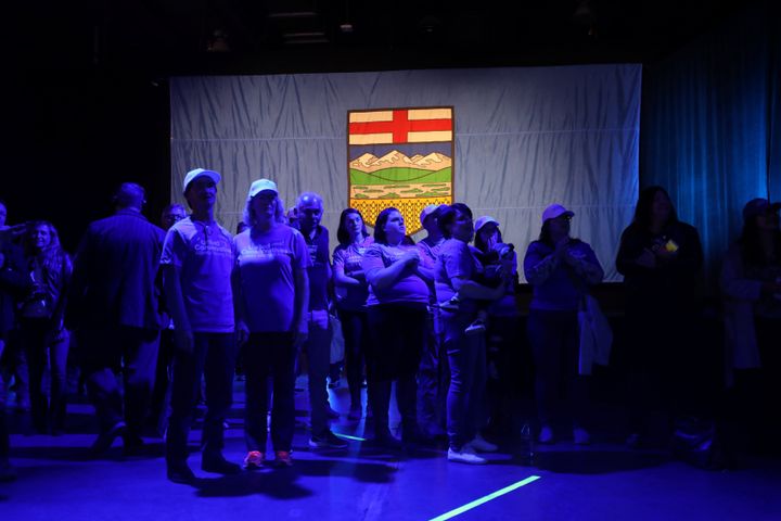 Supporters stand in front of the Alberta flag at the United Conservative Party election night headquarters in Calgary on April 16, 2019.
